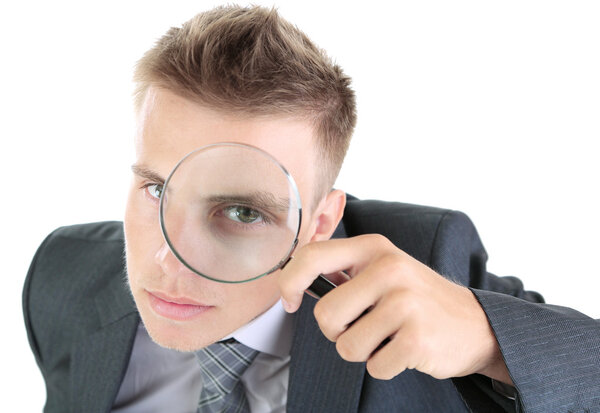 Young businessman looking through magnifying glass isolated on white