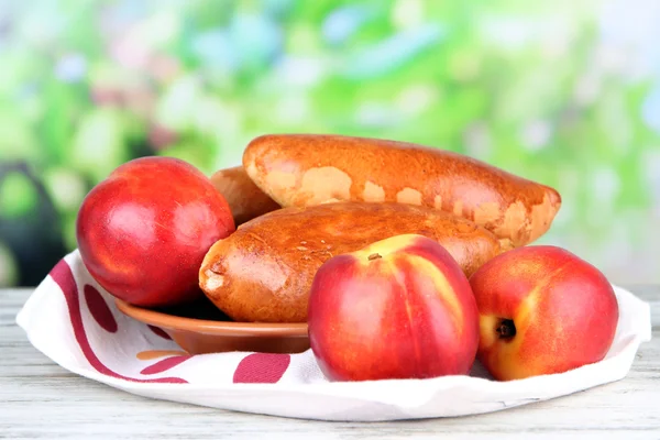 Fresh baked pasties with fruit jam, on wooden table, on bright background — Stock Photo, Image