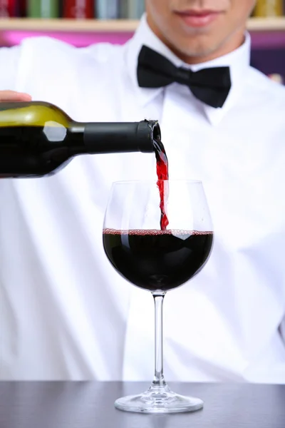 Bartender is pouring red wine into glass — Stock Photo, Image