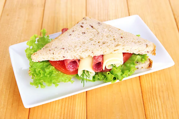 Sabroso sándwich con salchichas y verduras en plato blanco, sobre fondo de madera —  Fotos de Stock