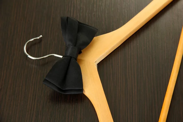 Black bow tie on wooden hanger, on wooden background — Stock Photo, Image