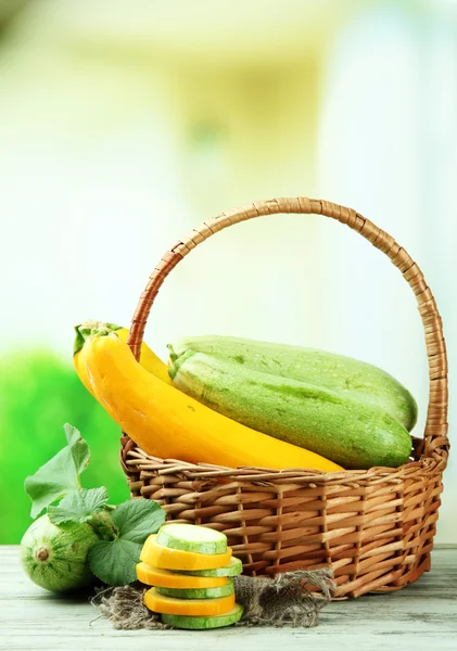 Sliced and whole raw zucchini in wicker basket, outdoors — Stock Photo, Image