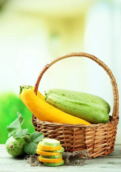 Gesneden en hele rauwe courgette in rieten mand, buitenshuis — Stockfoto