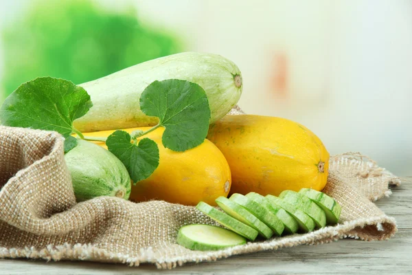 Gesneden en hele rauwe courgette op houten tafel, buiten — Stockfoto