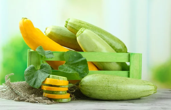 Gesneden en hele rauwe courgette in houten kist, buitenshuis — Stockfoto