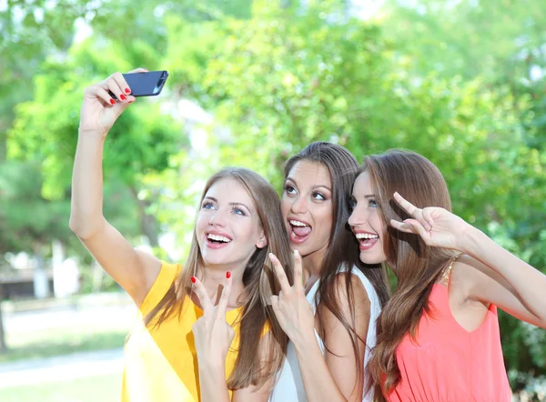 Drie mooie jonge vrouw nemen foto in zomer park — Stockfoto