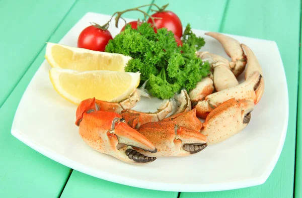 Kokt krabba klor på vit platta med salladsblad och tomater, på träbord bakgrund — Stockfoto
