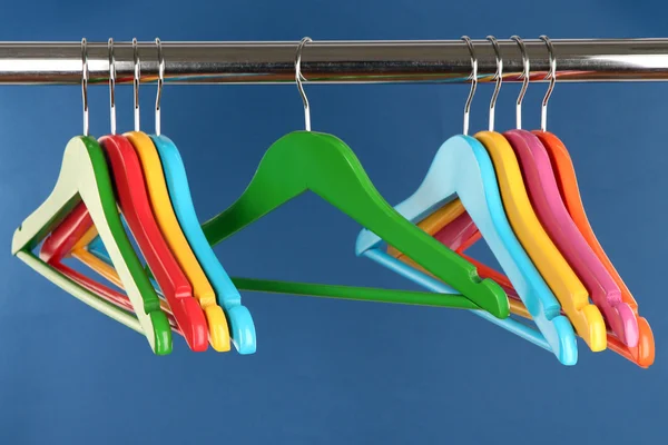 Colorful clothes hangers on blue background — Stock Photo, Image