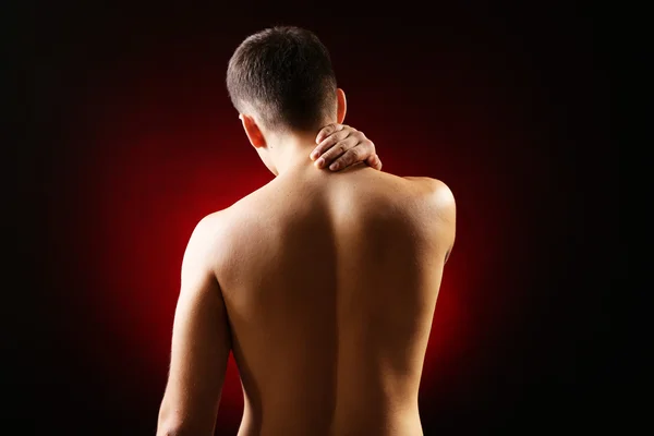 Young man with neck pain, on red background — Stock Photo, Image