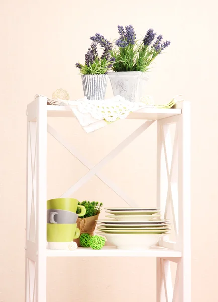 Krásné bílé police s nádobí a dekoracemi na zeď na barvu pozadí — Stock fotografie
