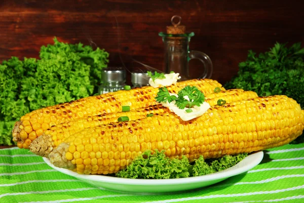 Delicioso maíz dorado a la parrilla con mantequilla en la mesa sobre fondo de madera — Foto de Stock