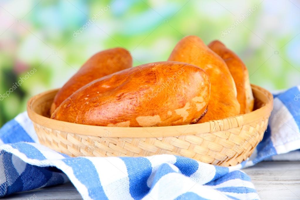 Fresh baked pasties, in wooden bowl, on wooden table, on bright background