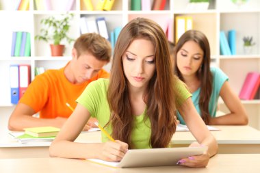 Kütüphanede oturan genç öğrenci grubu