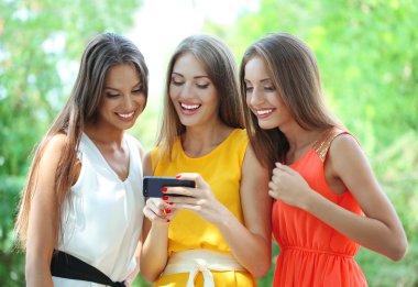 üç güzel genç kadın ile smartphone yaz Park