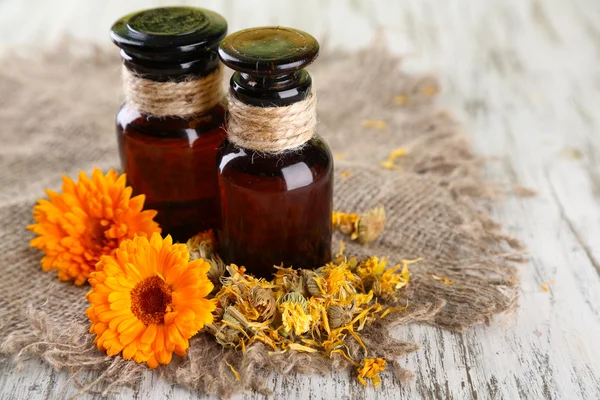 ilaç şişeleri ve ahşap zemin üzerine calendula çiçekler