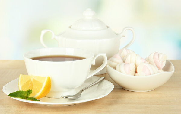 Чашка чая с лимоном на столе на светлом фоне
