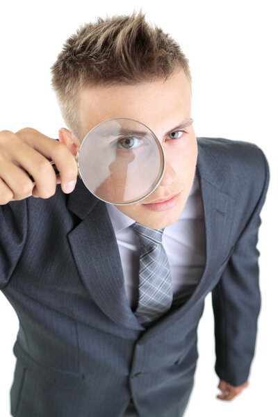 Young businessman looking through magnifying glass isolated on white