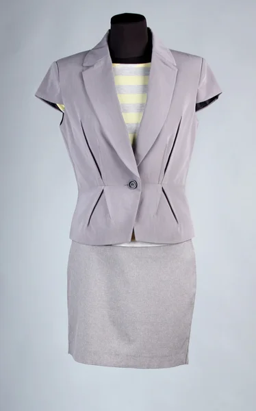 Gul blus, grå jacka och grå kjol på skyltdocka, på grå bakgrund — Stockfoto