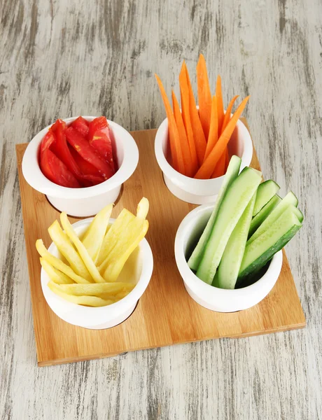 Verduras frescas brillantes cortan rebanadas en cuencos en la mesa de madera de cerca —  Fotos de Stock