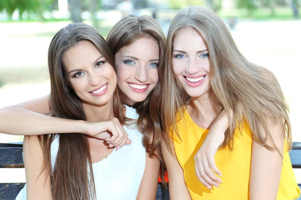 Three beautiful young woman sitting on bench in summer park — Stock Photo, Image