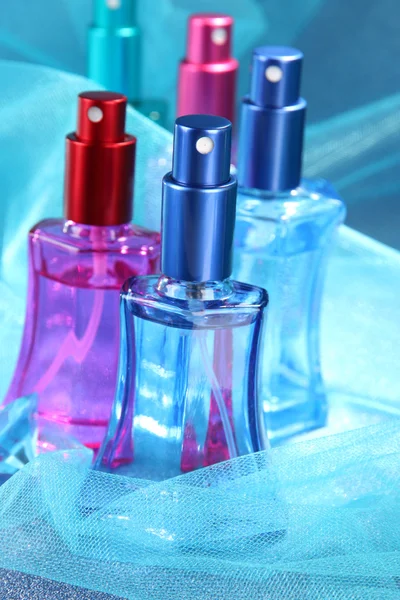 Perfume de mujer en hermosas botellas sobre fondo azul —  Fotos de Stock