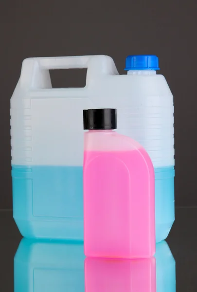 Синие и розовые жидкости для автомобиля в канистрах на сером фоне — стоковое фото