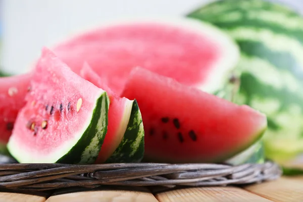 Mogen vattenmelon på wicker bricka på träbord på ljus bakgrund — Stockfoto