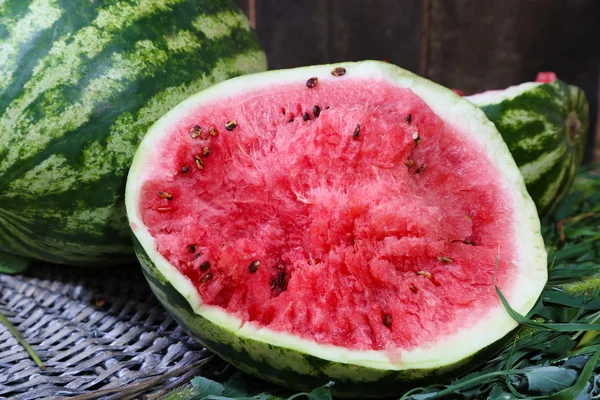 Mogen vattenmelon på wicker bricka på gräs nära stängslet — Stockfoto