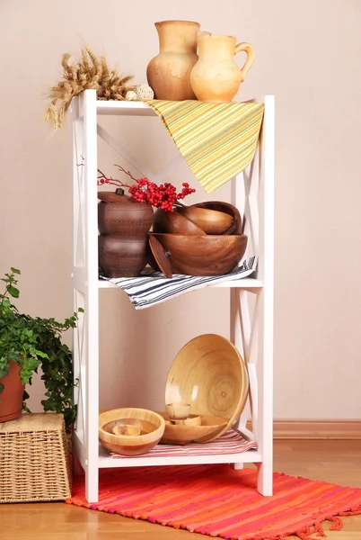 Prateleiras brancas bonitas com utensílios de mesa e decoração, no fundo da parede de cor — Fotografia de Stock