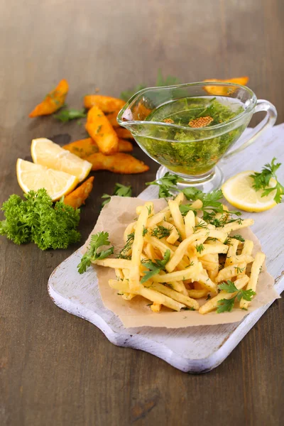 Batatas fritas no papel de rastreamento a bordo na mesa de madeira — Fotografia de Stock