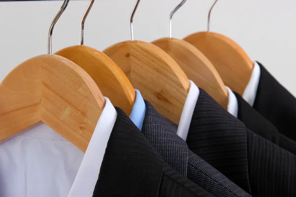 Trajes con camisas en perchas sobre fondo claro — Foto de Stock