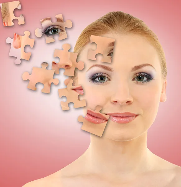 Mooi meisje met delen van de huid op puzzels op roze achtergrond — Stockfoto