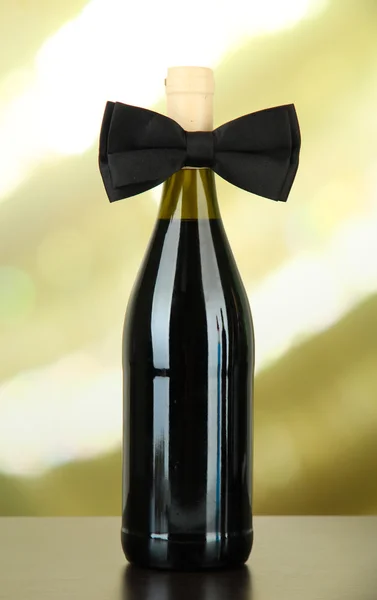 Black bow tie on wine bottle on bright background — Stock Photo, Image