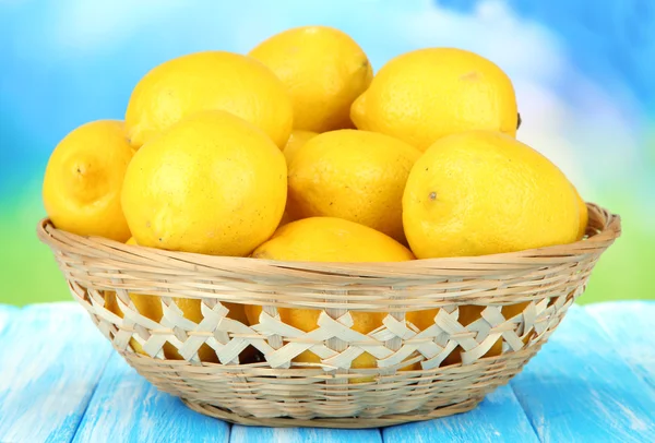 Limones maduros en canasta de mimbre sobre mesa sobre fondo brillante —  Fotos de Stock