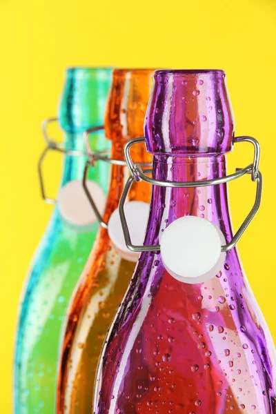 Botellas de colores sobre fondo amarillo — Foto de Stock