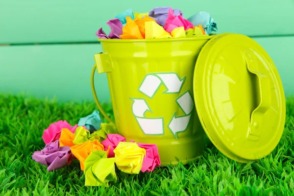 Recycling-Tonne auf grünem Gras auf hölzernem Hintergrund — Stockfoto