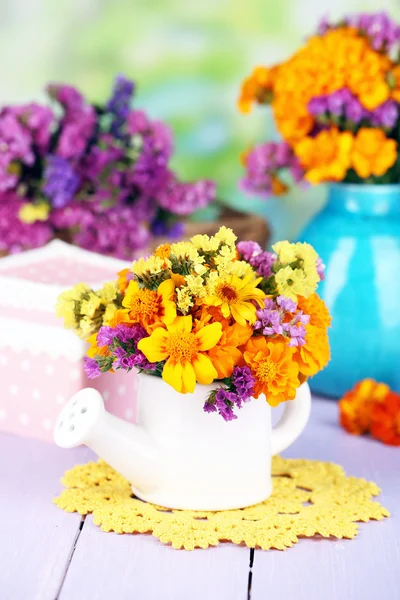 Bouquet of marigold flowers in watering can on wooden table on natural background — Stock Photo, Image