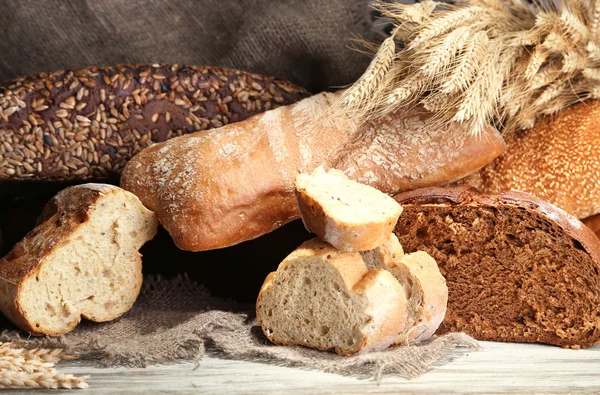 Veel brood op houten plank op rieten lade achtergrond — Stockfoto