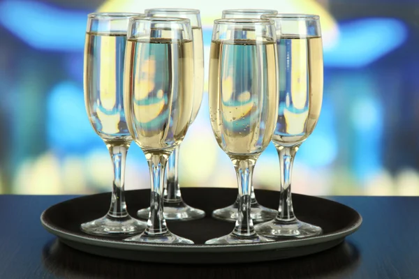 Many glasses of champagne on the tray on table, on bright background — Stock Photo, Image