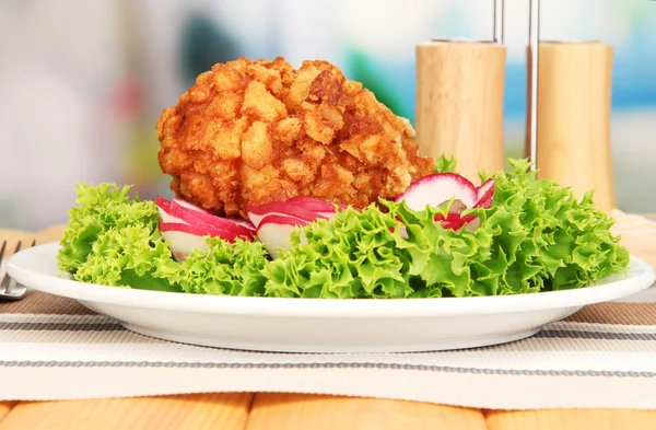 Chicken Kiev on croutons with lettuce salad, on wooden table, on bright background — Stock Photo, Image