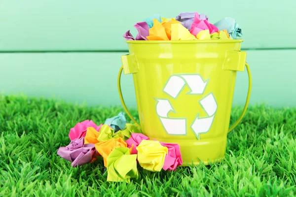 Reciclagem bin na grama verde na cor de fundo de madeira — Fotografia de Stock