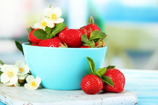 Ripe sweet strawberries in bowl on blue wooden table — Stock Photo, Image