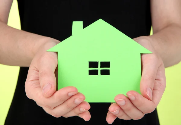 Paper house in hand on green background — Stok fotoğraf