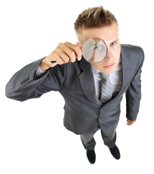 Young businessman looking through magnifying glass isolated on white