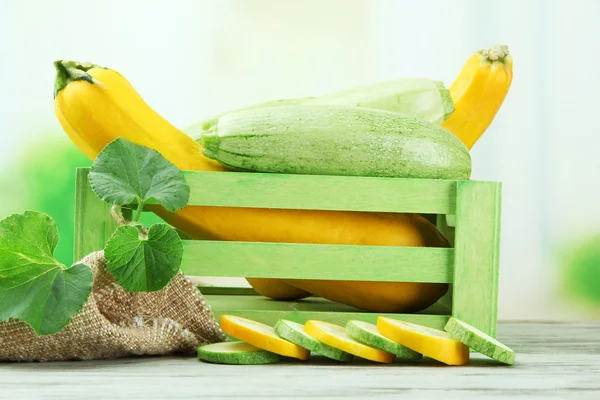 Skivad och hela råa zucchini i trälåda, utomhus — Stockfoto