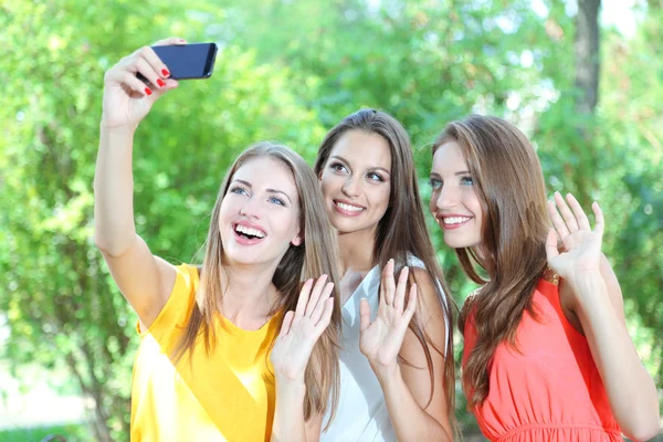 Drie mooie jonge vrouw nemen foto in zomer park — Stockfoto