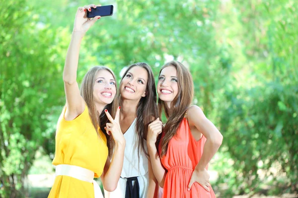 Trois belles jeunes femmes prenant des photos dans le parc d'été — Photo
