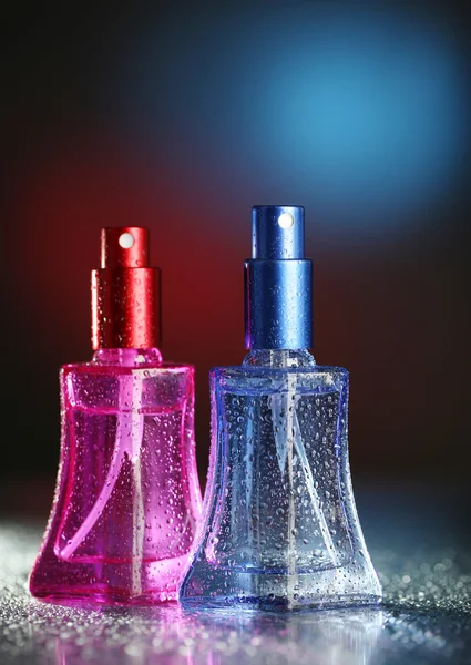Жіночі парфуми в красивих пляшках на темному тлі з кольоровим світлом — стокове фото