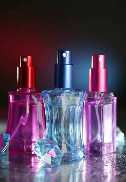 Women perfume in beautiful bottles on dark background with color light — Stock Photo, Image