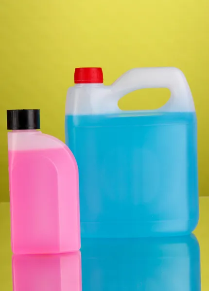 Blue and pink liquids for car in canisters on green background — Stock Photo, Image